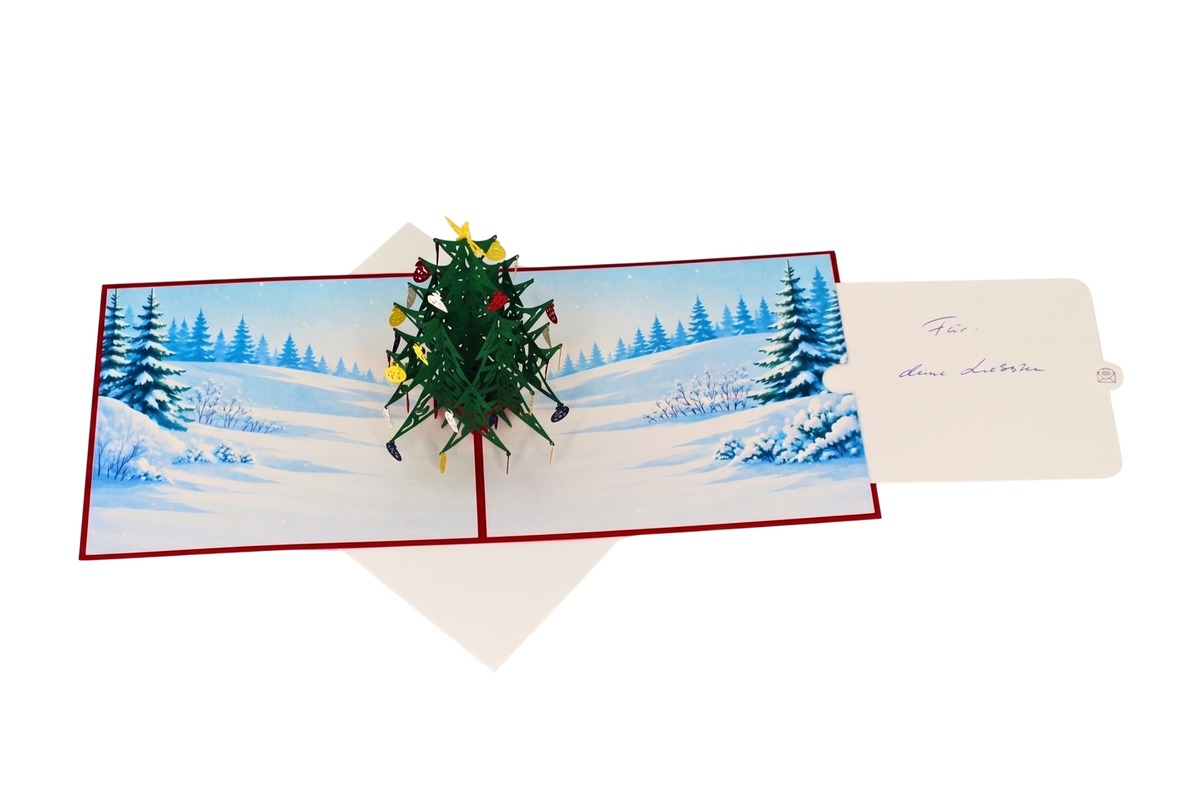 Pop-up-Weihnachtskarte von oben, rechts ragt ein Umschlag mit der handschriftlichen Widmung „Für deine Liebsten“ heraus
